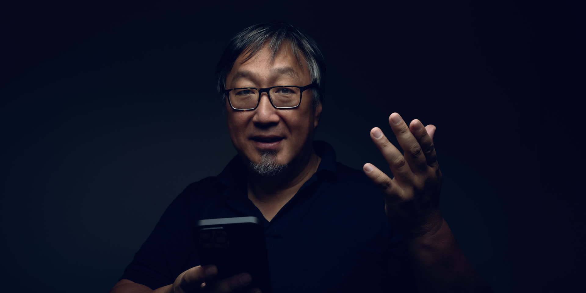 Kolja Chang, Gründer von Business X-Factor, mit Smartphone und einem wissenden Lächeln